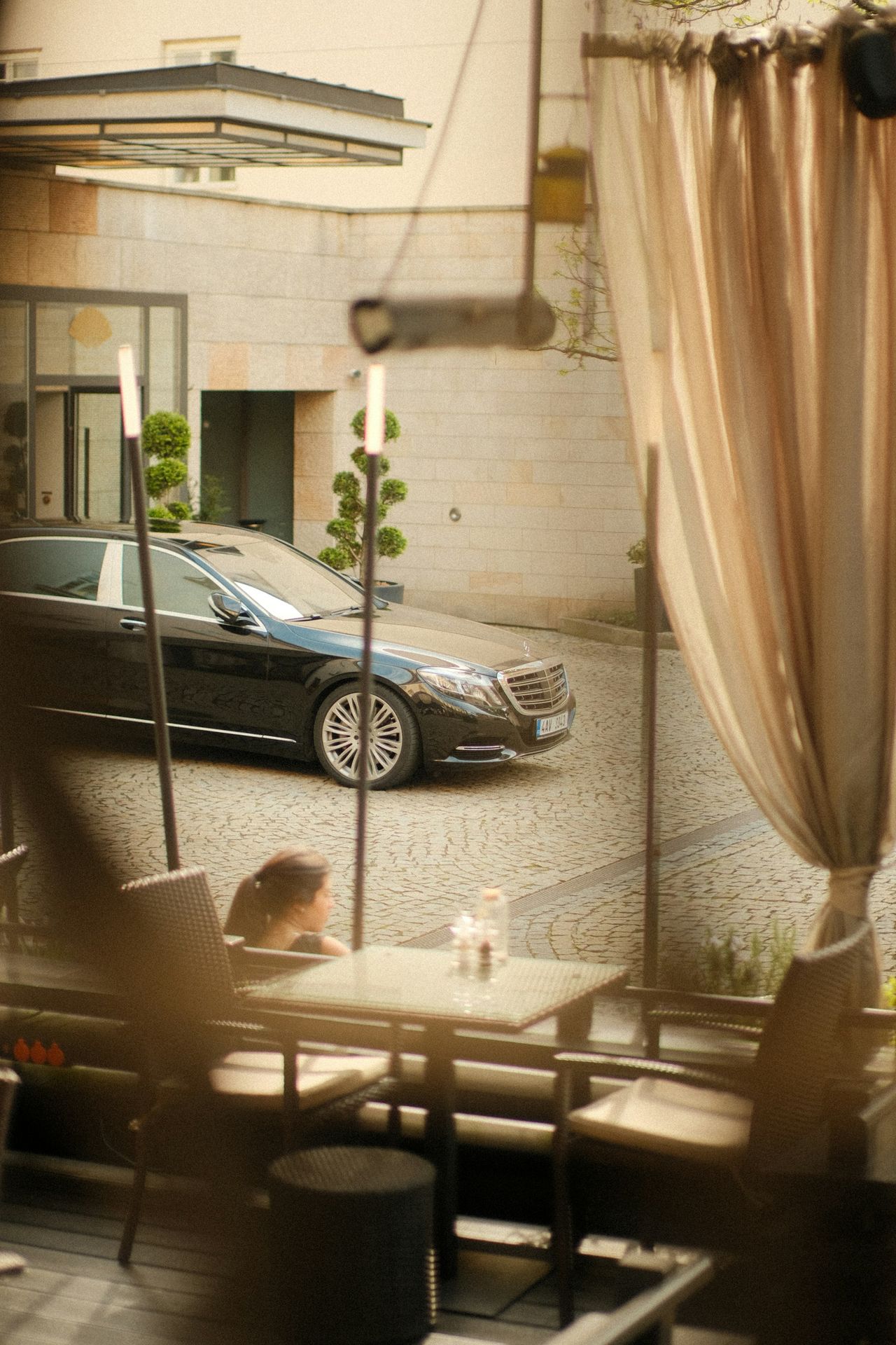 A luxury car parked near an outdoor dining area.